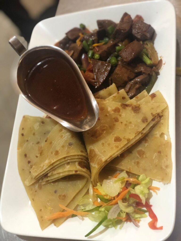 A plate featuring succulent liver pieces served alongside fluffy chapatis, a tempting dish available at Irman Restaurant and Cafe.