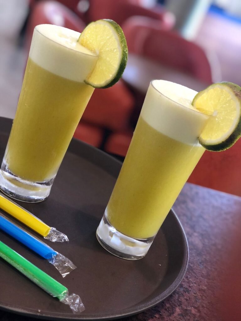 A glass filled with clear, golden apple juice adorned with a slice of fresh apple, served at Irman Restaurant and Cafe.