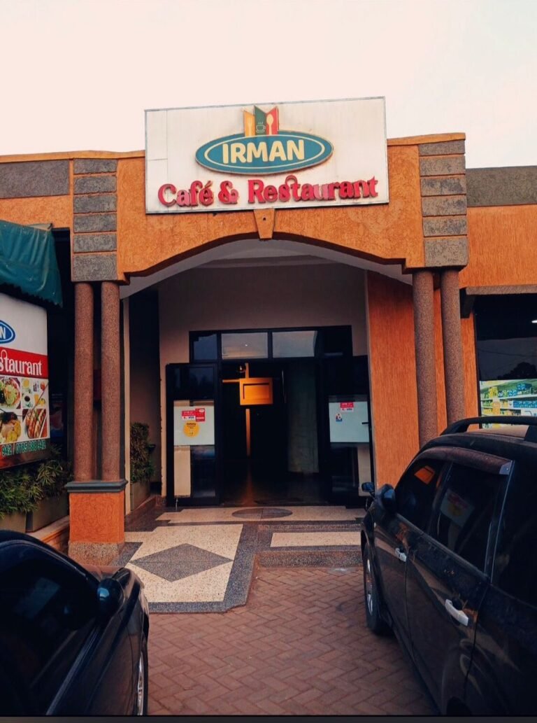 An image capturing the exterior facade of Irman Restaurant and Cafe, featuring large glass windows and a welcoming entrance.